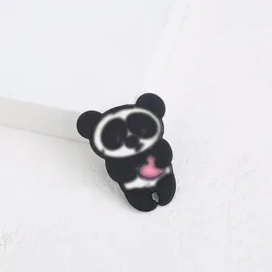 Gros plan sur une jolie broche panda en acrylique noir avec un détail de cœur rose vif original.