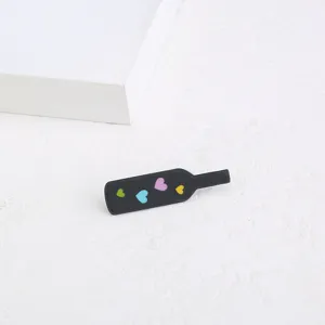 Gros-plan d'une broche en acrylique en forme de bouteille noire avec coeurs colorés.