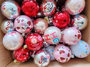 Detailed shot of assorted Christmas decorative balls in a box with festive painted patterns.