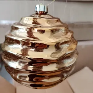 Golden electroplated Christmas ornament ball with unique wavy design for holiday tree decor.