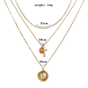 Collier multi-couches doré tendance avec pendentif croix et perle, chaîne élégante.