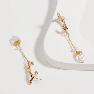 Gros plan des boucles d'oreilles pendantes perles fil de cuivre métal or lettre J.