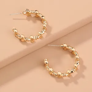 Close-up detail shot of gold-plated C-shaped hoop earrings with unique beaded texture design.
