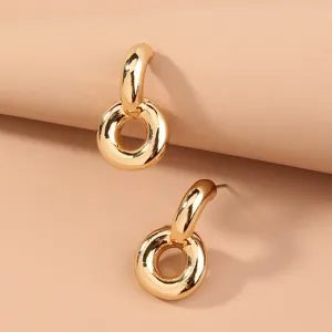 Primo piano di eleganti orecchini a cerchio in metallo dorato con anelli intrecciati chic.