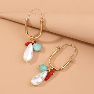 Detail shot of trendy gold-plated U-shaped hoop earrings with pearl and stone charms.