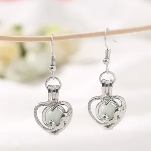 Pendientes plateados de corazon luminoso con bonito colgante de jaula animal hueca.