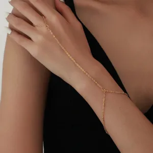 Detailopname van een fijn gouden handketting armband met minimalistische geometrische kralen.