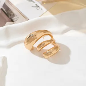 Close-up of chunky gold geometric spiral earring resting on white artistic ceramic dish.