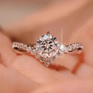Silver tone ring featuring a sparkling round center stone with pave band and accent cluster.