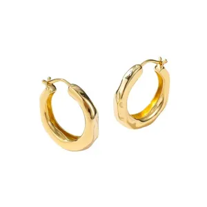 Close-up detail of the gold chunky hoop earrings, showing the smooth polished surface design.