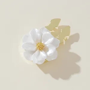 Close-up detail of white floral button cover featuring shiny gold tone metal base.
