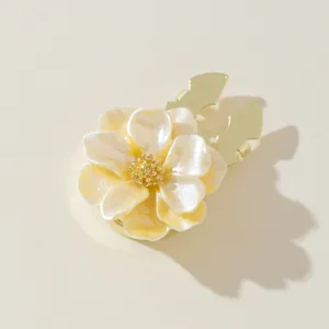 Floral button cover detail, pearl white and yellow petals with gold metal clip base.