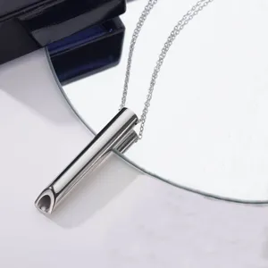 Detailed shot of stainless steel anxiety relief breathing necklace pendant on reflective mirror surface.