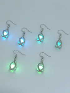 Detailansicht von leuchtenden Käfig-Ohrringen mit Hohlmetalldesign und glühenden Kugeln.