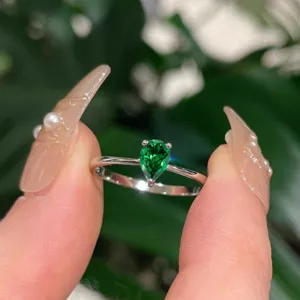 Primo piano dettagliato dell'anello con pietra verde a goccia, che esalta la fascia.