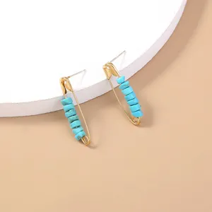 Closeup view of chic safety pin stud earrings featuring turquoise beads, bohemian detail.