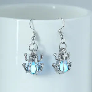 Leuchtende Frosch Ohrringe Detailaufnahme, silberne Hänge Ohrringe mit leuchtender Perle.