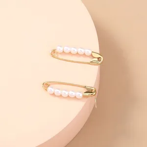 Gold-plated safety pin earrings decorated with delicate white pearls, minimalist style.