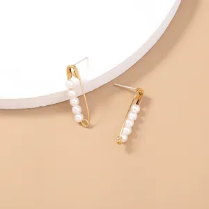 Pearl safety pin earrings detail shot, minimalist gold tone metal design closeup view.