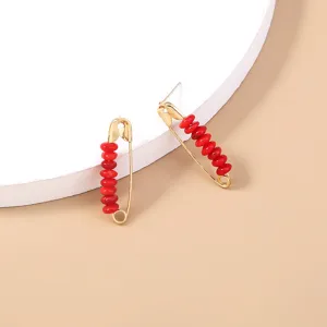 Gold safety pin earrings featuring vibrant red disc beads, chic bohemian style jewelry.