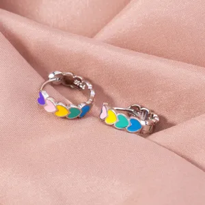 Close-up detail of silver hoop earrings featuring colorful enamel hearts on satin.