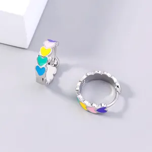 Close-up detail of colorful heart enamel hoop earrings with vibrant multi-color metal design.
