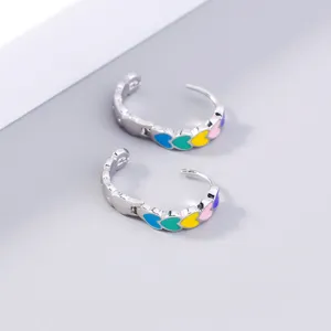 Close-up detail shot of colorful enamel heart hoop earrings in metallic silver finish.
