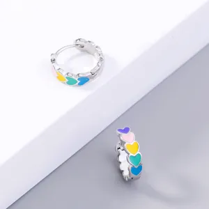 Detailed view of silver-tone hoop earrings decorated with colorful enamel heart patterns.