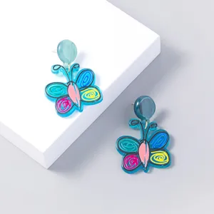 Detailed close-up of blue butterfly acrylic earrings with colorful graffiti details.