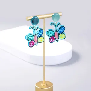 Detail view of colorful acrylic butterfly drop earrings on a gold stand, chic fashion jewelry.