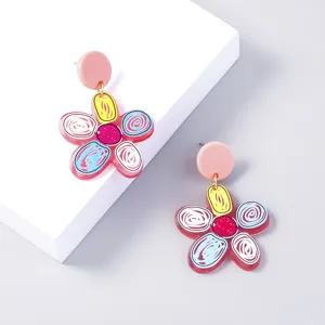 Close-up view of colorful floral drop earrings, cute acrylic design with pink stud.
