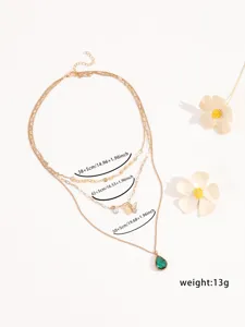 Primo piano della collana dorata multistrato con ciondoli a farfalla e pietra verde.