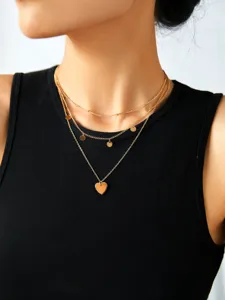 Primo piano dettagliato di una elegante collana a catena dorata multistrato con ciondoli.