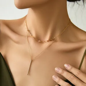 Elegante collana dorata a doppio strato con maglie geometriche e ciondolo a barra.