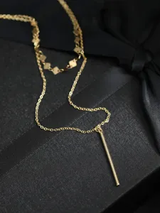 Primo piano dettagliato di una collana d'oro multistrato con elegante ciondolo a barra.