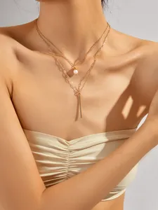 Bellissima collana girocollo doppia dorata con perla d'acqua dolce e pendente a barra metallica.