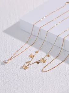 Squisita collana dorata multistrato con delicato ciondolo di perla e charm a farfalla.
