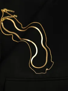 Primo piano dettagliato di una collana a catena dorata a doppio strato con piccolo dettaglio.