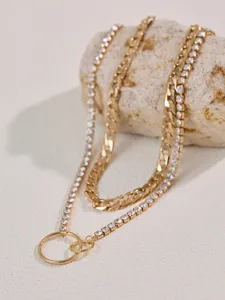 Vista dettagliata della collana a catena d'oro con strass multistrato e anello.