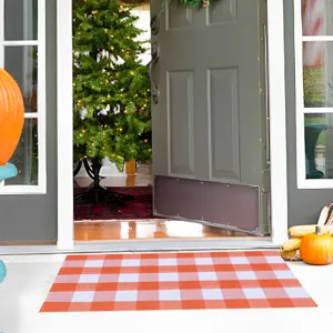 Orange and white buffalo check doormat for front porch entrance, festive seasonal decor.