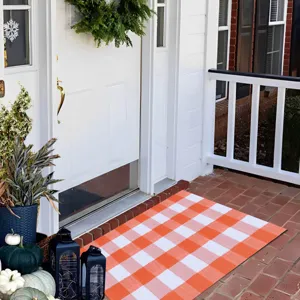 Orange white checkered door mat, stylish entrance rug for home porch decoration and cleaning.
