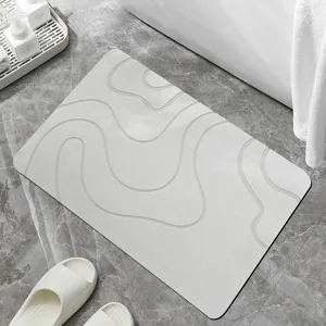 Grey diatomaceous earth bath mat with minimalist wavy embossed design for quick water absorption.