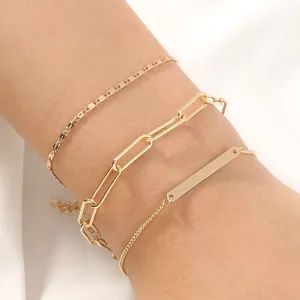 Conjunto de pulseras de cadena doradas por capas, detalle de eslabones y colgante de barra.