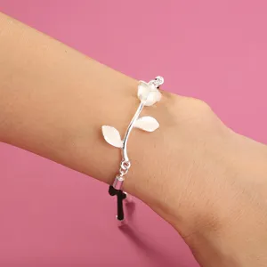 Detailansicht eines silbernen Rosenblüten Armbands mit schwarzer Kordel, modischer Schmuck.