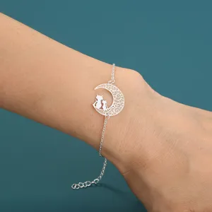 Nahaufnahme eines silbernen Armbands mit Mondsichel und Katzen Anhänger am Handgelenk.