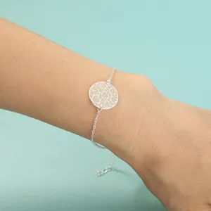 Nahaufnahme des silbernen Armbands mit hohlem Herzanhänger, elegante Detailansicht am Handgelenk.