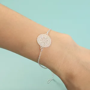 Nahaufnahme des filigranen silberfarbenen Armbands mit hohlem runden Motiv am Handgelenk.