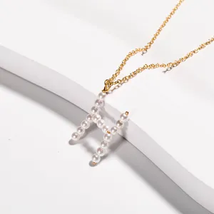 Collana con catena dorata e ciondolo lettera H intarsiato di perle, gioielli minimal.