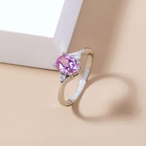 Dettaglio di un anello da donna minimalista squisito con uno zircone rosa ovale e pietre.