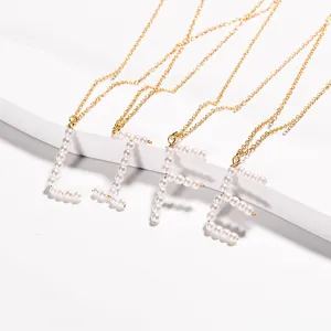 Primo piano dettagliato di collane d'oro con eleganti ciondoli di lettere in perle LIFE.
